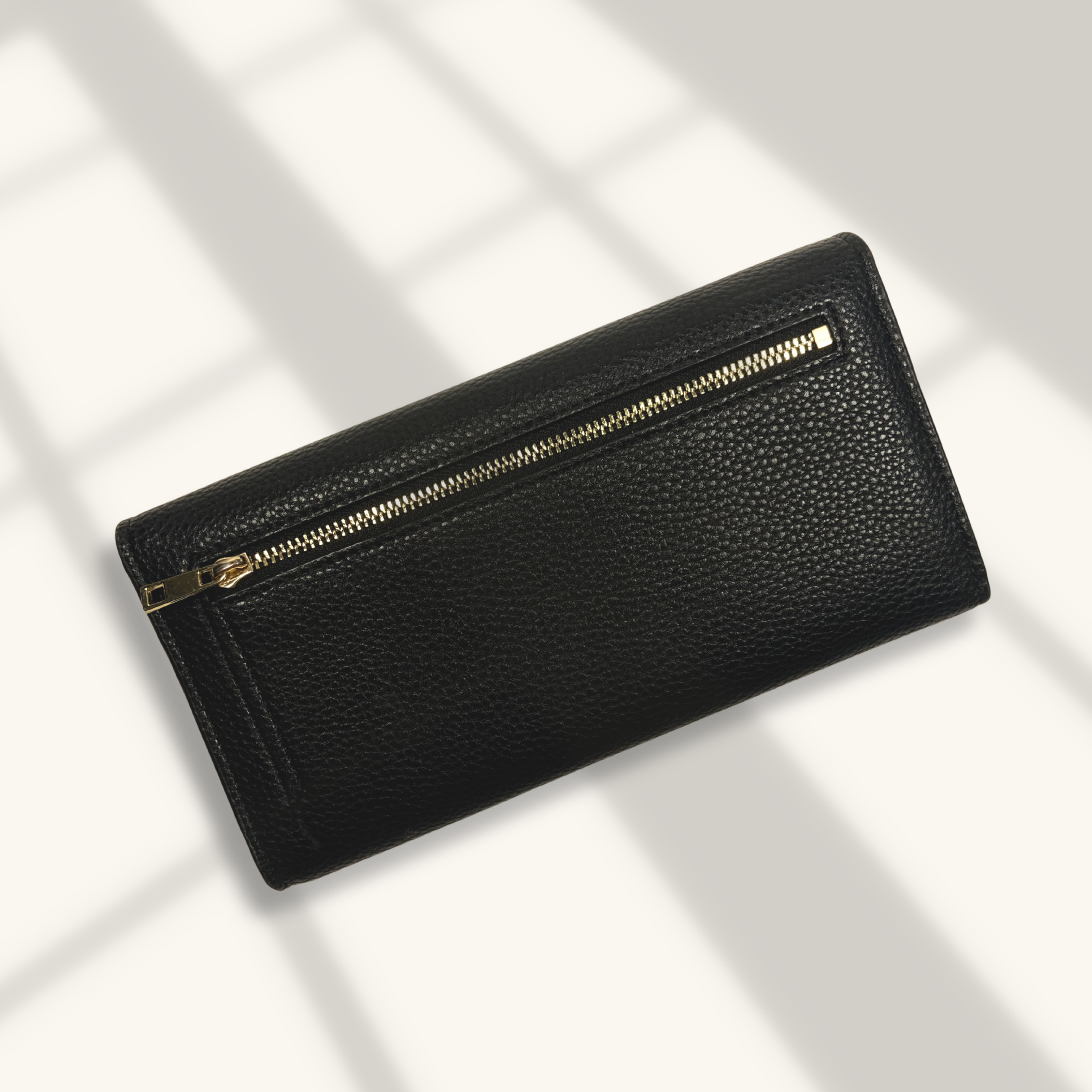 Black leather wallet with a gold zipper on a light background