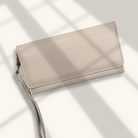 Beige leather wallet with wrist strap on a light background