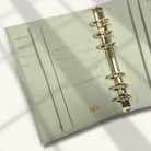 Light green planner with gold binding on a light background
