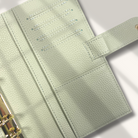 Light green leather planner with gold binding on a white background