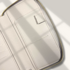 Close-up of a light beige leather wallet with gold zipper on a white background