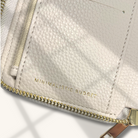 Close-up of a beige textured wallet with gold zipper and 'Minimalistic Budget' text on a white background